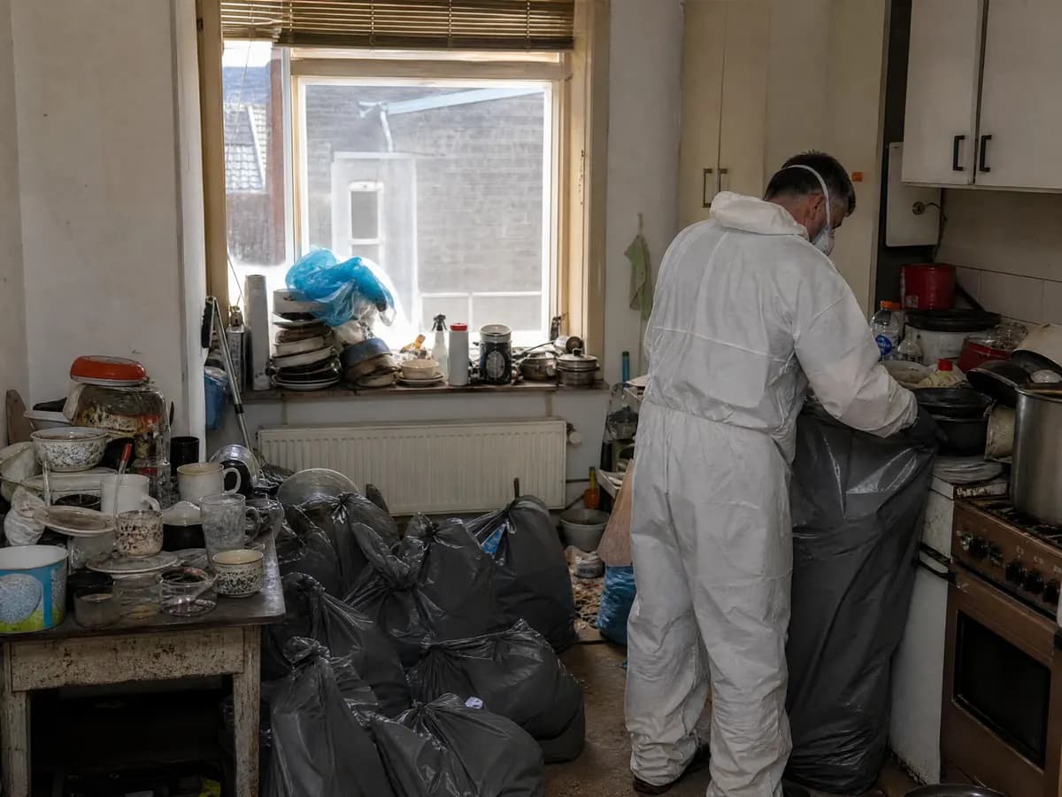 Opruimers in beschermkledij ruimen een vervuilde keuken op